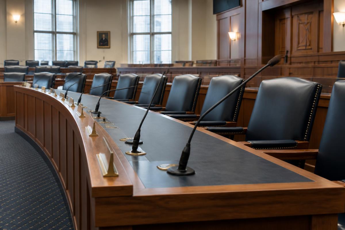 An empty regulator hearing room with nameplates and microphones in daylight